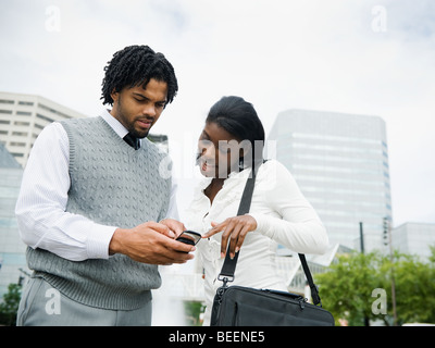Imprenditore e imprenditrice guardando il cellulare in città Foto Stock