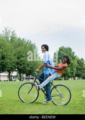Giovane equitazione bicicletta in posizione di parcheggio Foto Stock