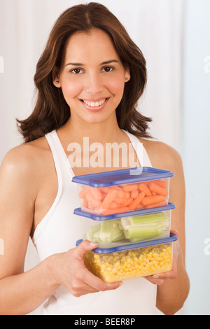 Donna ispanica tenendo le verdure in plastica Contenitori di archiviazione Foto Stock