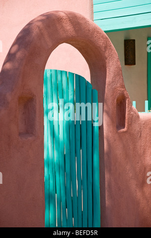 Un arco di adobe e giardino in legno cancello in Taos, Nuovo Messico. Foto Stock