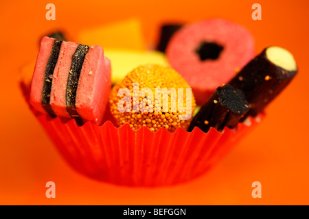 Liquirizia Allsorts in rosso cupcake caso di carta con sfondo arancione Foto Stock