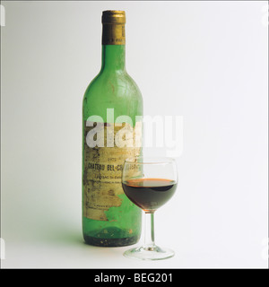 Vuoto 1975 'Chateau Bel-Chouteau' il vino rosso di Bordeaux bottiglia con etichetta danneggiata e wineglass Foto Stock