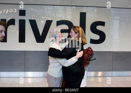 Saluto emotivo dopo la lunga assenza in arrivi internazionali concourse a Heathrow il terminal 5. Foto Stock