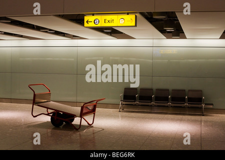 International sala reclamo bagagli posti a sedere e bagagli Skycap barrow a Heathrow il Terminal 5. Foto Stock