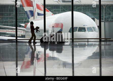 Una giovane ragazza getta il suo giocattolo pet tigre nella parte anteriore di un BA 777 aereo di linea in una finestra di partenza dell'aeroporto di Heathrow T5 Foto Stock