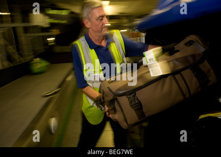 A British Airways i carichi dei bagagli dei passeggeri per i beni in un contenitore di compagnie aeree a Heathrow Terminal 5. Foto Stock