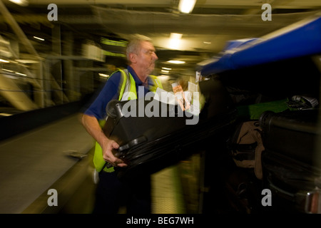 A British Airways i carichi dei bagagli dei passeggeri per i beni in un contenitore di compagnie aeree a Heathrow Terminal 5. Foto Stock