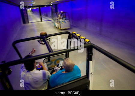 Gli infermi e gli anziani il transito di passeggeri trasportati attraverso il tunnel in buggy attraverso l'aeroporto di Heathrow il terminal 5 Foto Stock