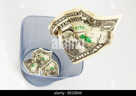 Immagine composita della US Dollar Bills dollari gettati in un cestino per carta su sfondo semplice dal di sopra per illustrare USA sprecare denaro concept Foto Stock