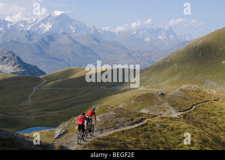 Due mountain bike cavalcare un singletrack trail in Les Arcs nelle Alpi francesi, con il Mont Blanc in background. Foto Stock