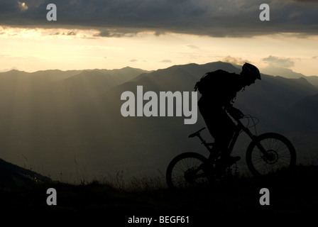 Silhouette di un mountain biker al tramonto nelle montagne di Les Arcs nelle Alpi francesi. Foto Stock