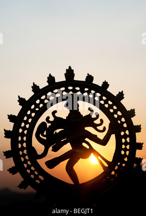 Dancing signore Shiva statua, Nataraja silhouette, contro un indiano sunrise. Puttaparthi, Andhra Pradesh, India Foto Stock