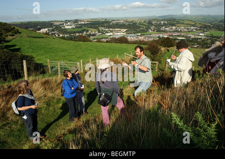 Un botanico con il Consiglio di campagna per il Galles che portano un bio-diversità natura a piedi fino Pendinas Hill fort, Aberystwyth, Galles Foto Stock