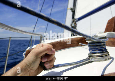 Estate blu acqua e cielo in una gara di barche a vela, marinaio uomo nel verricello Foto Stock