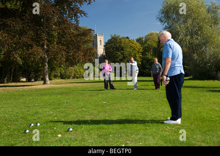 Inghilterra, Cambridgeshire, Huntingdon, Hartford, pensionati giocando a bocce su riverside verde sotto il campanile della chiesa Foto Stock