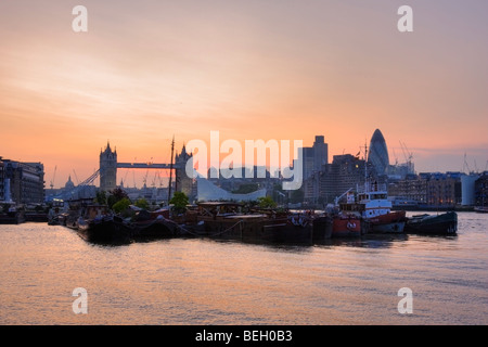 Tramonto dietro il Tower Bridge di Londra con Bermondsey house barche in silhouette sul Fiume Tamigi. Foto Stock