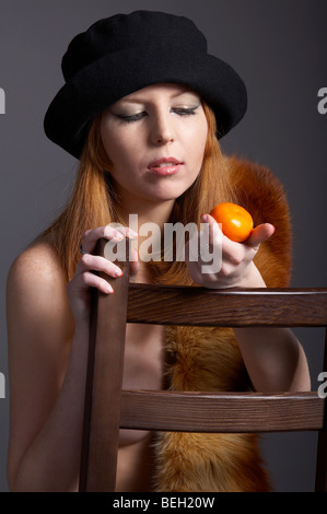 Ritratto di bella rossa pallido modello scuoiati in pelliccia fox, sciarpa e cappello nero con mandarine Foto Stock