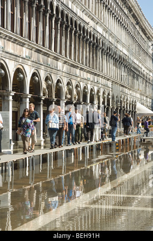 La gente che camminava sul duckboards sollevata in piazza San Marco Venezia dopo un allagamento Foto Stock