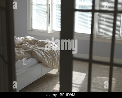 Letto disfatto con increspato coperta in una camera da letto Foto Stock