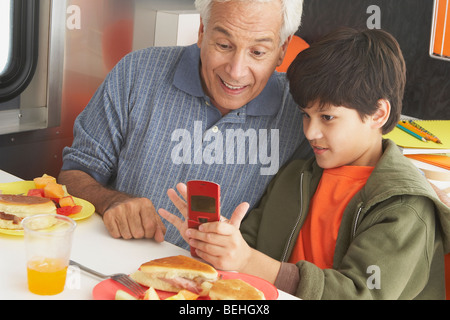 Ragazzo insegnamento suo nonno come usare un telefono cellulare Foto Stock