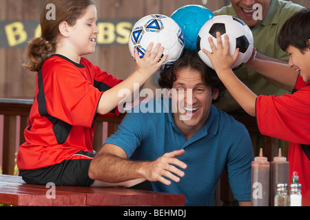 Metà uomo adulto a giocare con la sua famiglia in un ristorante Foto Stock