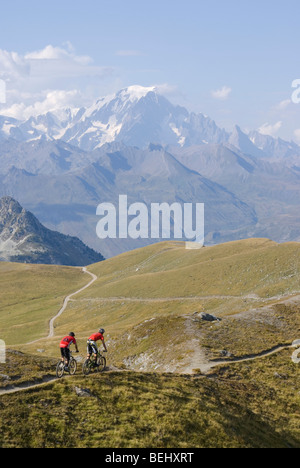 Due mountain bike cavalcare un singletrack trail vicino a Les Arcs nelle Alpi francesi, con il Mont Blanc in background. Foto Stock