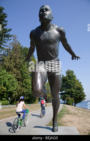 Due persone a cavallo passato una statua di un uomo che corre in Stanley Park, Vancouver Foto Stock