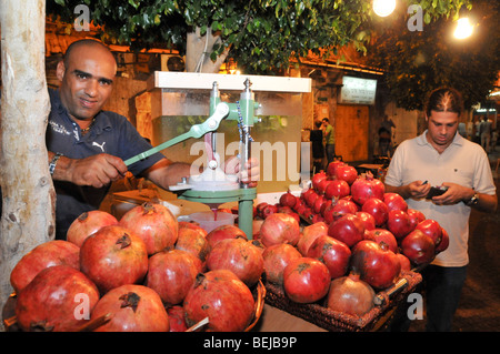 Israele, acro, man spreme fresco succo di melograno in una fase di stallo nel mercato Foto Stock