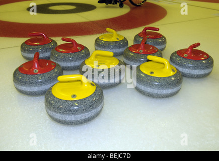 Giallo e Rosso pietre di Curling su ghiaccio. Foto Stock