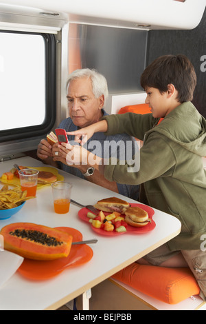 Il profilo laterale di un ragazzo di insegnamento a suo nonno come usare un telefono cellulare Foto Stock