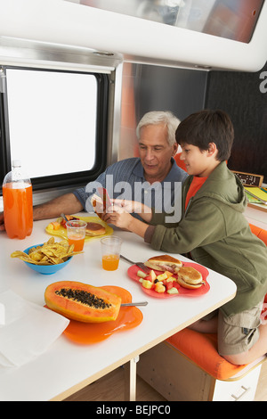 Il profilo laterale di un ragazzo di insegnamento a suo nonno come usare un telefono cellulare Foto Stock