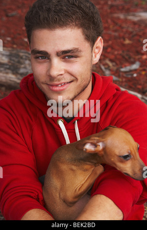 Ritratto di un giovane uomo sorridente con un cane Foto Stock