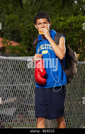 Ragazzo adolescente ascoltando un ipod e mangiare empanada Foto Stock