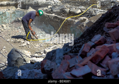 Operaio edile scava in un cantiere utilizzando un jackhammer Foto Stock