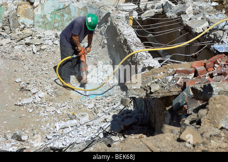 Operaio edile scava in un cantiere utilizzando un jackhammer Foto Stock