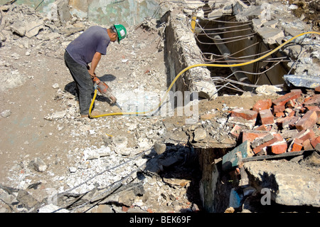 Operaio edile scava in un cantiere utilizzando un jackhammer Foto Stock