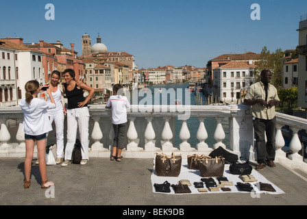 Falsi falsi falsi beni di marca borse mercato nero che vendono in piena vista delle autorità. Oggetti di lusso contraffatti. Ponte degli Scalzi. Venezia Italia Foto Stock