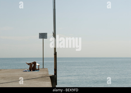 Venezia Italia Venezia Lido mare Adriatico la spiaggia pubblica. Donna che legge prendere il sole evitando altre persone in vacanza. HOMER SYKES 2000 Foto Stock