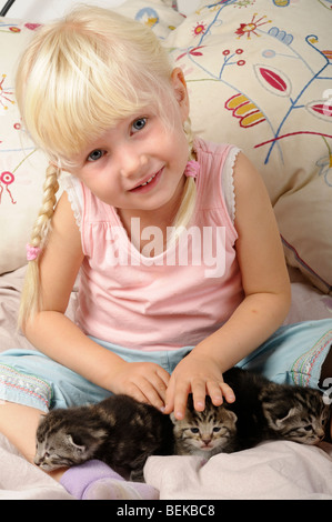 Stock Foto di un po' di 4 anno vecchia ragazza giocare con i suoi gattini. Foto Stock