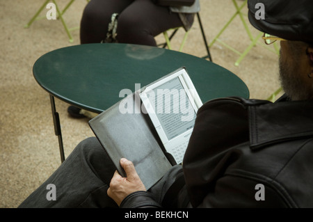 Un lettore utilizza il suo Amazon Kindle libro elettronico sulla strada a Midtown Manhattan a New York Foto Stock