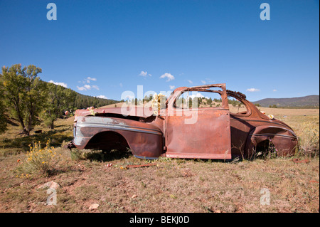 Un vecchio arrugginito auto sconosciuto di marca e modello si trova sul pendio di una collina in miniere d'oro città fantasma di Elizabethtown, Nuovo Messico. Foto Stock