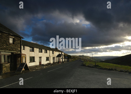 Il Kirkstone Pass Inn, il secondo più alto pub in Inghilterra su una burrascosa serata con le scure nuvole e sole Foto Stock