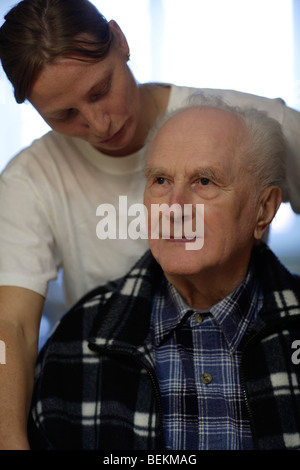 L uomo non valido in sedia a rotelle con terapista femmina Foto Stock