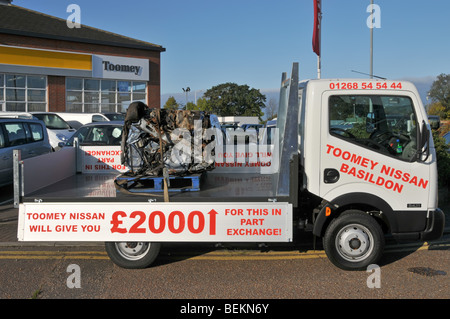 Nissan auto concessionario pick-up camion che trasporta una vecchia auto schiacciata come promozione per il governo auto scrappage schema Essex concessionaria Inghilterra UK Foto Stock