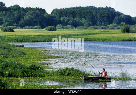 L'uomo la pesca dalla barca a remi sul lago in Sualki, Polonia Foto Stock