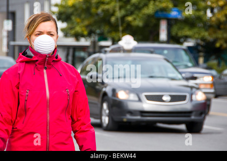 Donna che indossa una maschera protettiva il traffico della strada Foto Stock