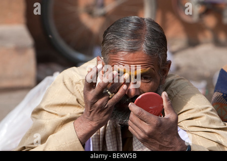 Pashupatinath, Nepal. Adoratore in Nepal il più sacro tempio indù che cercano in uno specchio come egli si prepara a decorare il suo volto. Foto Stock