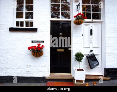 Casa bianca con il nero porta e finestra di nero cill accanto alla casa con porta bianca con una borsa nera pendenti da gestire. Foto Stock