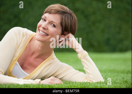 Donna sdraiata su erba sorridente Foto Stock