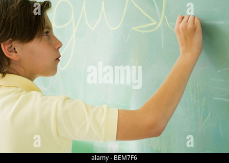 Ragazzo scrivere in corsivo sulla lavagna Foto Stock